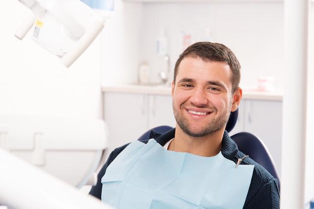 man smiling in the dental chair after dental care