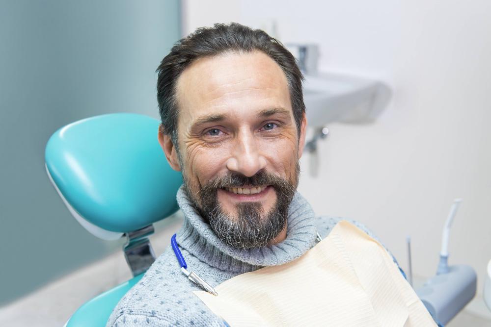 man smiling in dental chair after getting emergency dental treatment