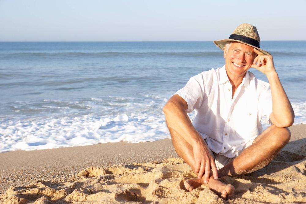 man sitting on beach smiling