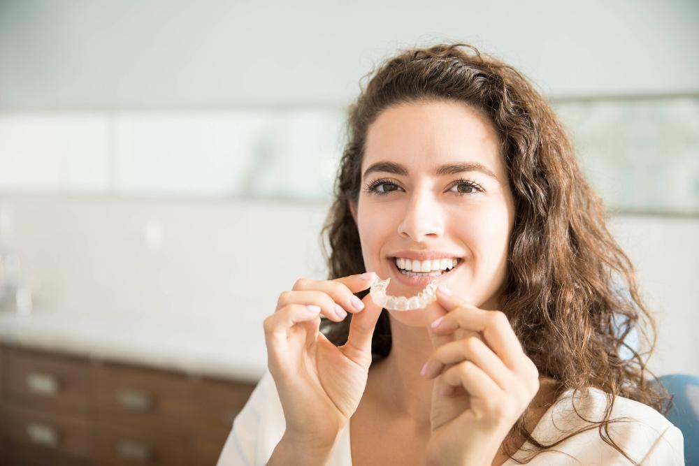 woman smiling while holding invisalign
