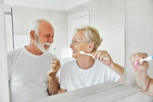 An elderly couple smiling while brushing teeth after a cost effective payment plan in Darwin, NT