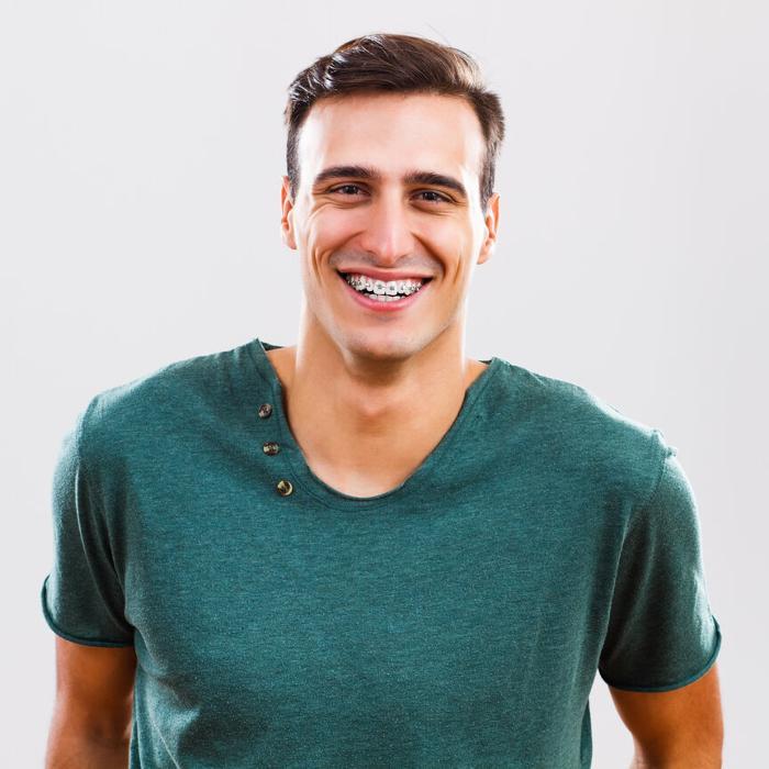 young adult smiling with metal braces on teeth