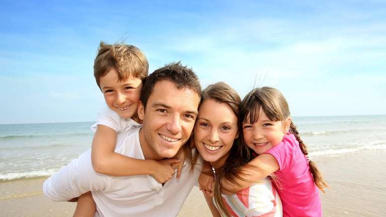 family of four smiling on beach