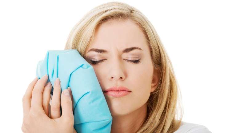 woman holding an ice pack to sore jaw