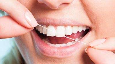 close up of woman flossing between front teeth