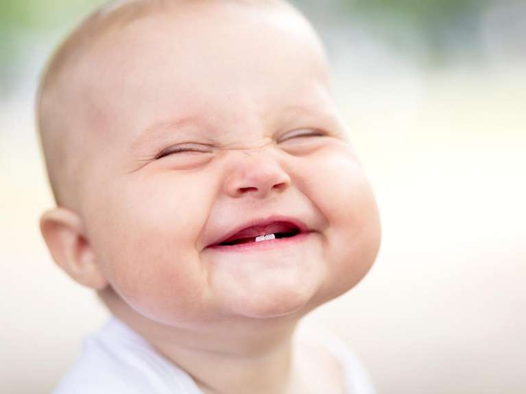 Smiling baby with two emerging teeth.