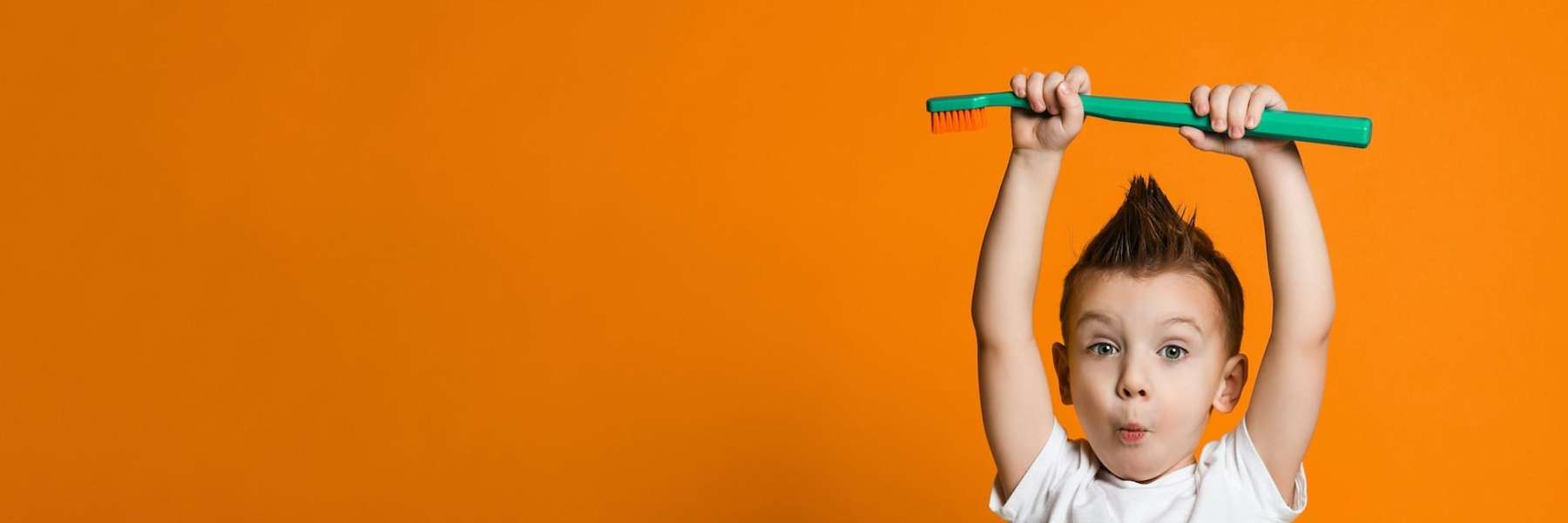 young boy holding a large toothbrush