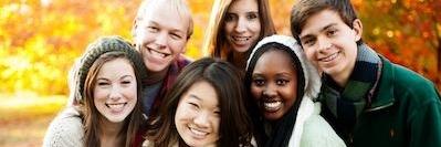 group of young teens smiling with fall leaves in background